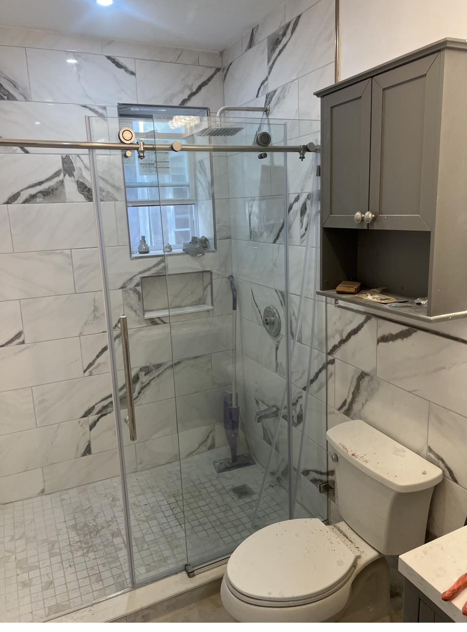 Frameless glass shower with marble tile walls
