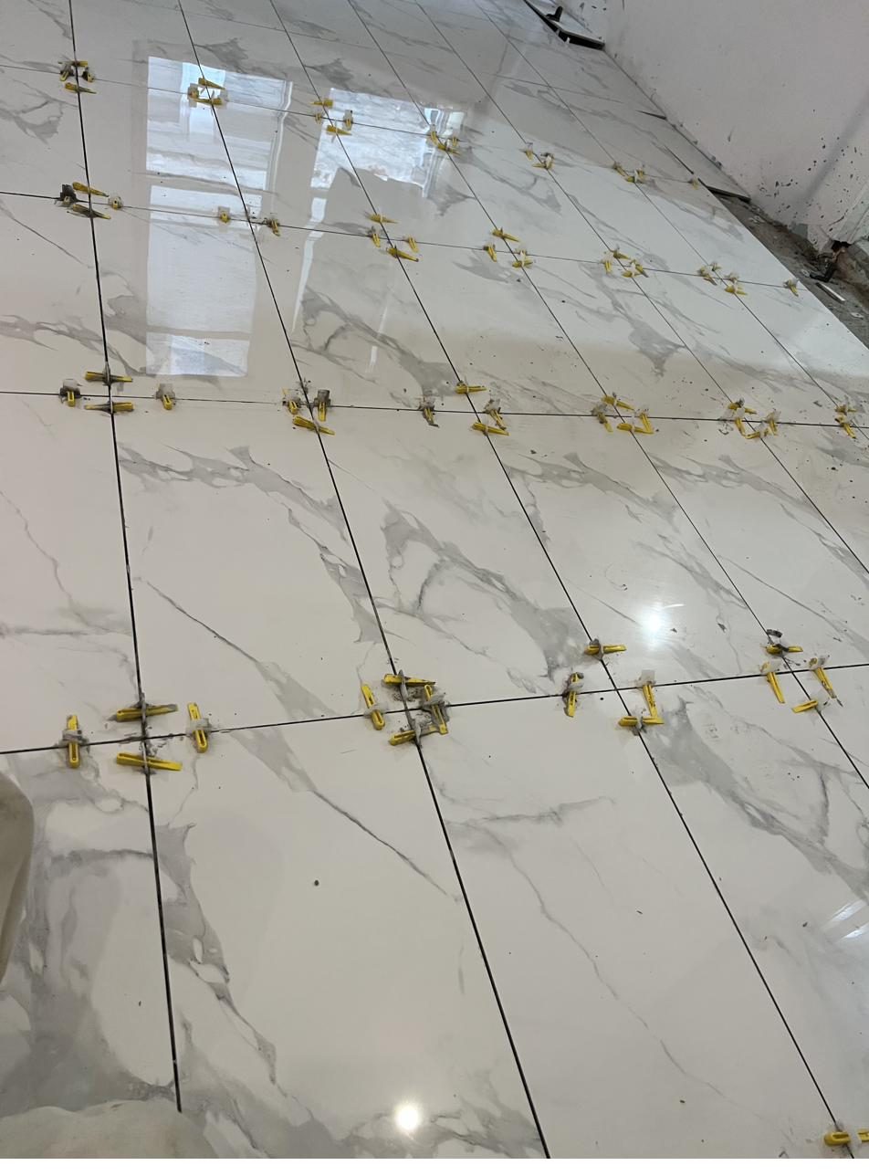 Large format tile being set with leveling clips